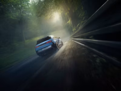 A Hyundai IONIQ 5 N high-performance EV seen from behind driving on a racetrack with trees.